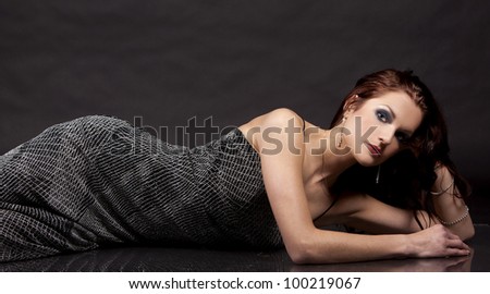 pretty brunette wearing silver fashion dress on black background