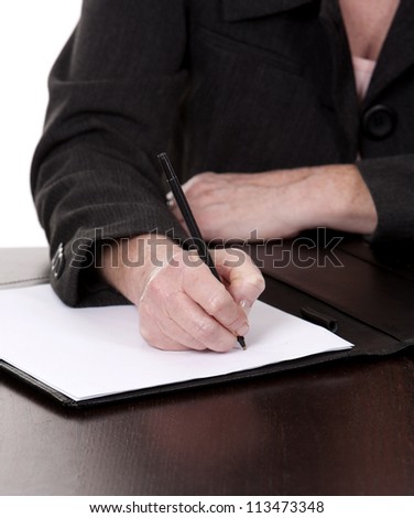 mature woman sitting behind desk and writing notes down