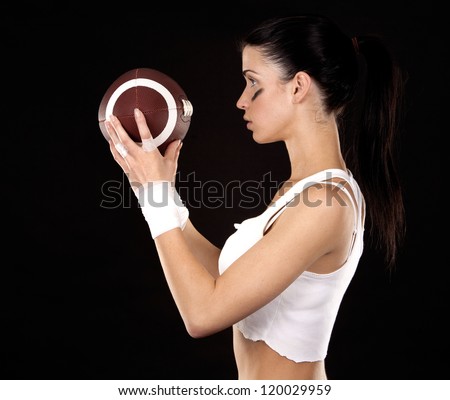 athletic brunette posing as american football girl on black background