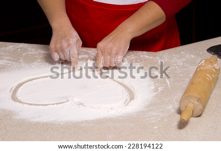 woman drawing into flour heart shape
