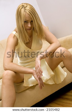 pretty blond female wearing evening gown sitting on sofa