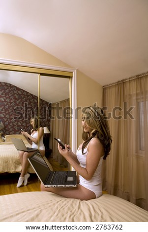 beautiful woman wearing white underwear and posing in her bed talking on the phone and using laptop