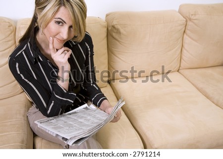 beautiful woman sitting on the sofa in living room wearing businesss wear and reading newspaper