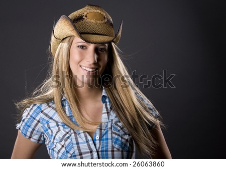beautiful blond woman wearing cowboy outfit on grey