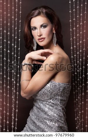 pretty brunette wearing silver party dress on black background