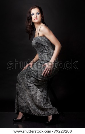 pretty brunette wearing silver fashion dress on black background