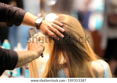 Hairdresser combing hair of young girl by hairbrush