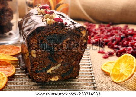Christmas cake with with dried plums and chocolate icing on wooden background