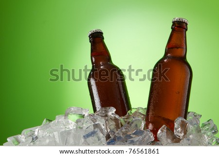 two beer bottles getting cool in ice cubes. Isolated on a green.