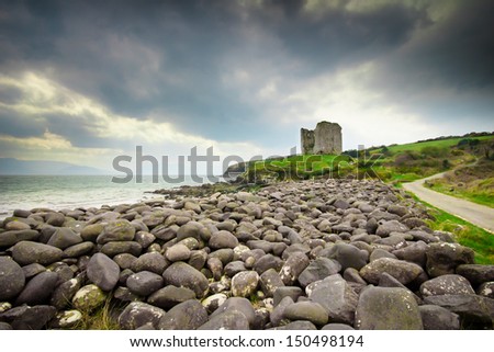 Rocky coast leading up to castle ruins along the Dingle coast in Ireland