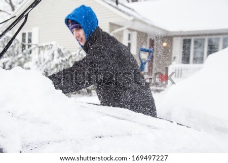 WEST HEMPSTEAD,  NY - JAN 3:  Teenager clears snow from his car on Long Island, NY on Jan 3 2014 after snow storm. This powerful nor'easter named Hercules caused blizzard conditions on Long Island.