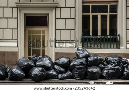Pile of black plastic trash bags on sidewalk