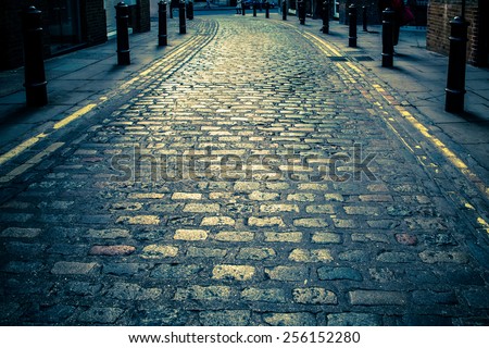 Vintage toned image of Old cobblestone road in London UK