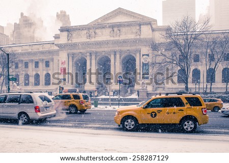 NEW YORK CITY - FEBRUARY 21, 2015:  Snow falling outside historic New York Public Library in Manhattan as cars go by.