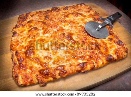 Delicious Italian cheese pizza on a cutting board with slicer