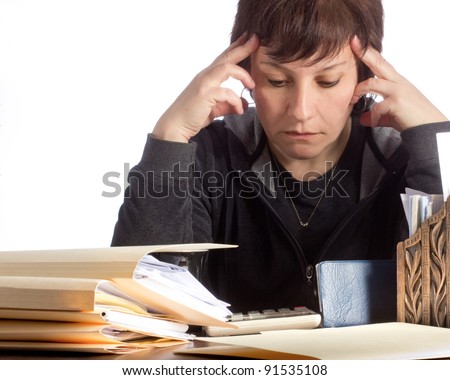 Serious woman, surrounded by files, checkbook and calculator,  in deep thought as she works on finances