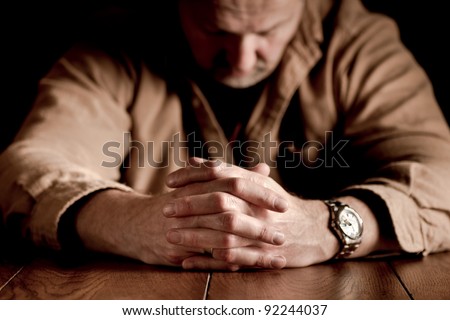 Dark, emotional image of clasped hands on troubled man