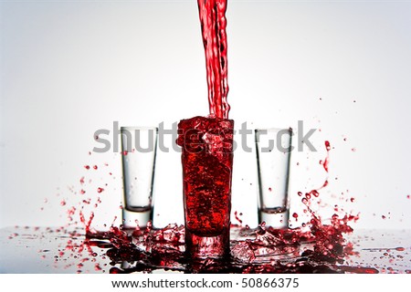 red liquid splashes into shot glass