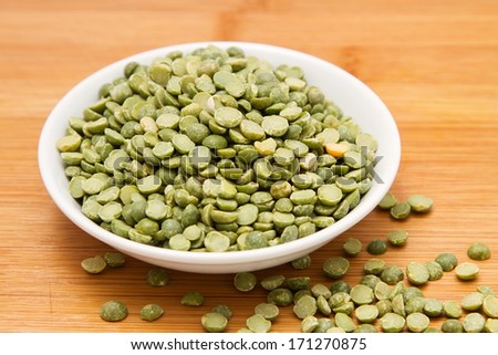 Green peas in white bowl on wooden tabletop