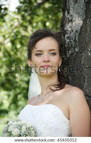 Portrait of Ukrainian fiancee with a wedding bouquet in hands, stands under a birch