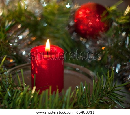 Christmas candle with a wreath and red ornament, with bokeh stars reflecting off silver tinsel