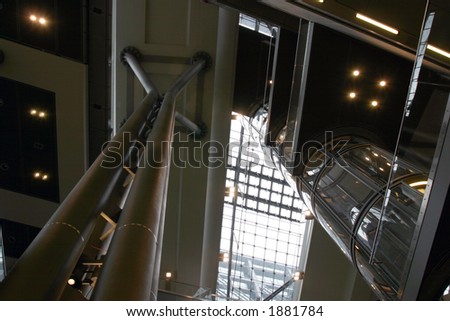 Contemporary public space interior. Modern glass tube elevator on the first plane.