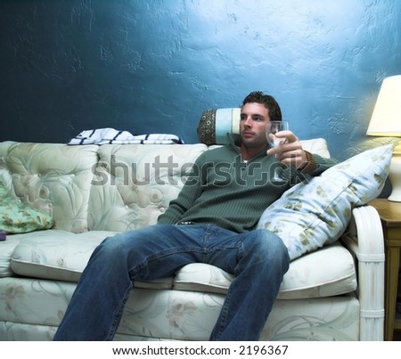 man sitting on couch enjoying a glass of?