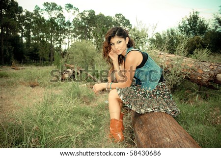 Imaged Are made To Look like old Camera style Picture Of a Cowgirl sitting on A log, (Picture is made With old School intended) Such as Effects added a fringing and  Blur