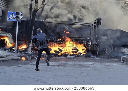 KIEV UKRAINE -FEBRUARY 18, 2014: Fire protecting by defend oneself protesters of  armed special forces attack at first day of mass shooting at Euromaydan time. Unknown young protester tosses a stone