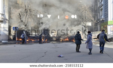 KIEV UKRAINE FEBRUARY 18, 2014: Day of mass shooting of Euromaydan protesters. The unarmed participators of march of resistance on Institutska street looks at armed special forces behind flaming cars