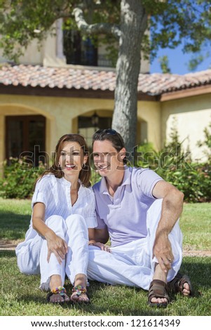 An attractive, successful and happy middle aged man and woman couple in their forties, sitting together outside under a tree and smiling.
