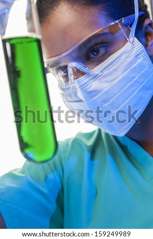 Asian female medical or scientific researcher or doctor looking at a test tube of green solution in a laboratory