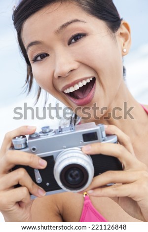 Chinese Asian girl young woman laughing taking vacation photograph in a bikini at the beach using a digital camera