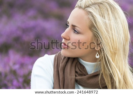 A naturally beautiful young blond woman in a field of purple heather flowers