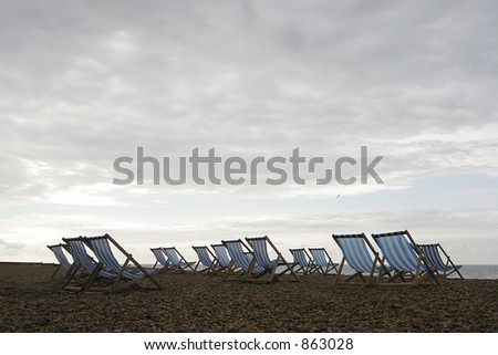 A group of empty deckchairs on a cloud covered beach in the early morning