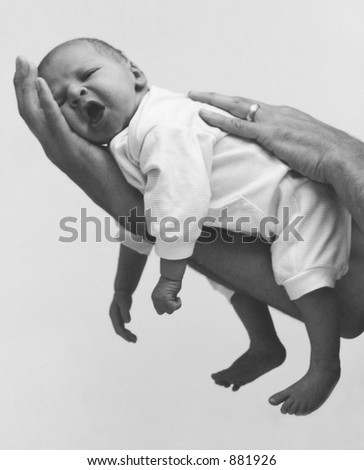A yawning baby resting on his father\'s hand. (Noise visible)