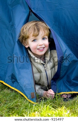 A young boy emerges from a tent on a camping trip