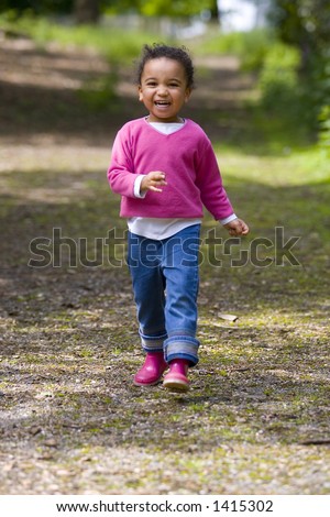 A beautiful mixed race girl walking down a path through the woods and laughing.
