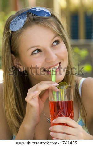 A pretty girl drinking a tall drink outside enjoying the summer sunshine.