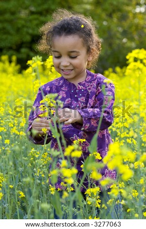 A beautiful mixed race girl looks having fun in a field full of yellow flowers