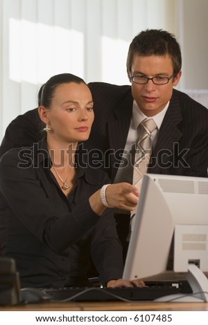 A male and female office worker looking together at a computer monitor