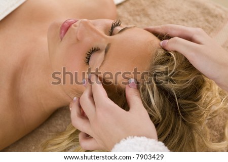 A young blond woman receiving a relaxing head massage from a beauty therapist