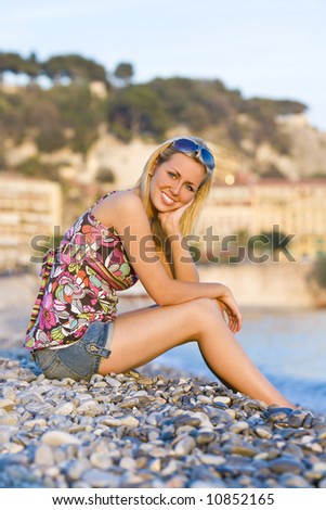 A beautiful young blond woman on a beach in the evening glow as the sun goes down