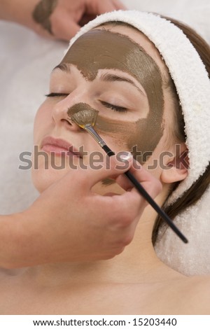 A beautiful young brunette woman having a chocolate face mask applied by a beautician