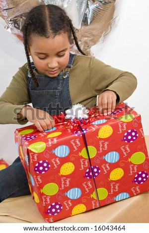 A beautiful young mixed race girl opening a huge birthday present
