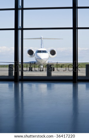 A small twin engined private corporate jet waits outside an airport terminal.