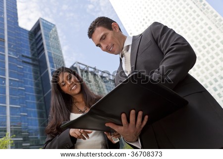 A smiling Asian businesswoman and her male colleague taking part in a business meeting outside in a modern city environment