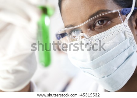 Environmental concept shot of a female Asian medical or scientific researcher or doctor looking at a test tube of a green solution in a laboratory.