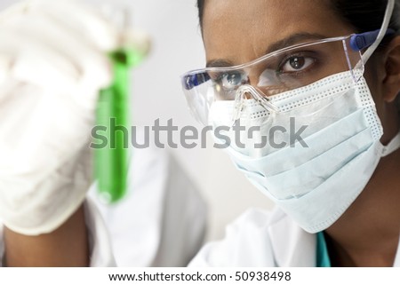 An Asian medical or scientific researcher or doctor looking at a test tube of green solution in a laboratory.