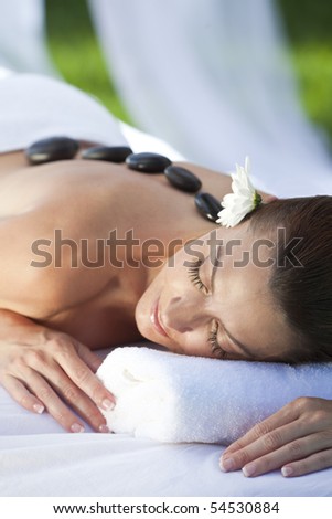 A woman relaxing at a health spa while having a hot stone treatment or massage